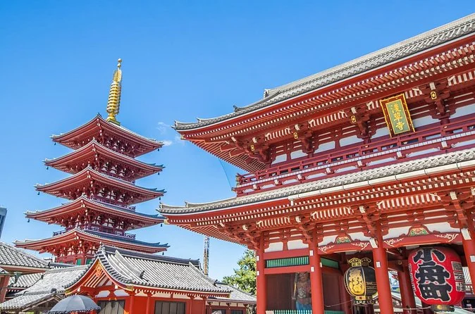 Senso-ji's red Hozomon gate with its hanging lanterns and the five-storey pagoda on the left under a blue sky