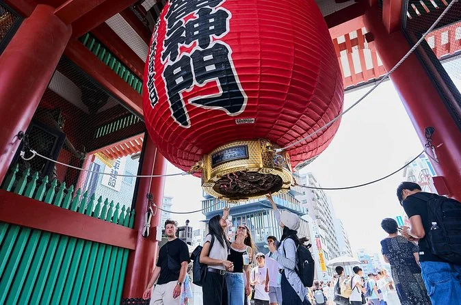 Looking up at the giant red Kaminarimon lantern from below, with visitors gathered under the gate